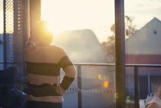 Woman watching sunset from home. Photo: iStock /