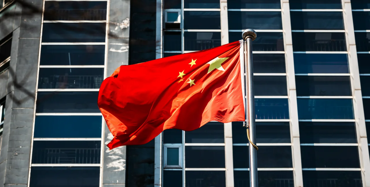 Chinese flag in front of skyscrapers. Photo: iStock, niuniu