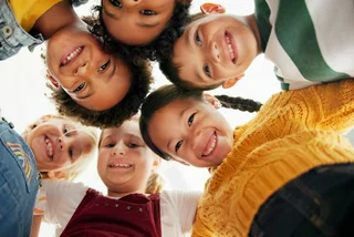 Children smiling and looking down at camera