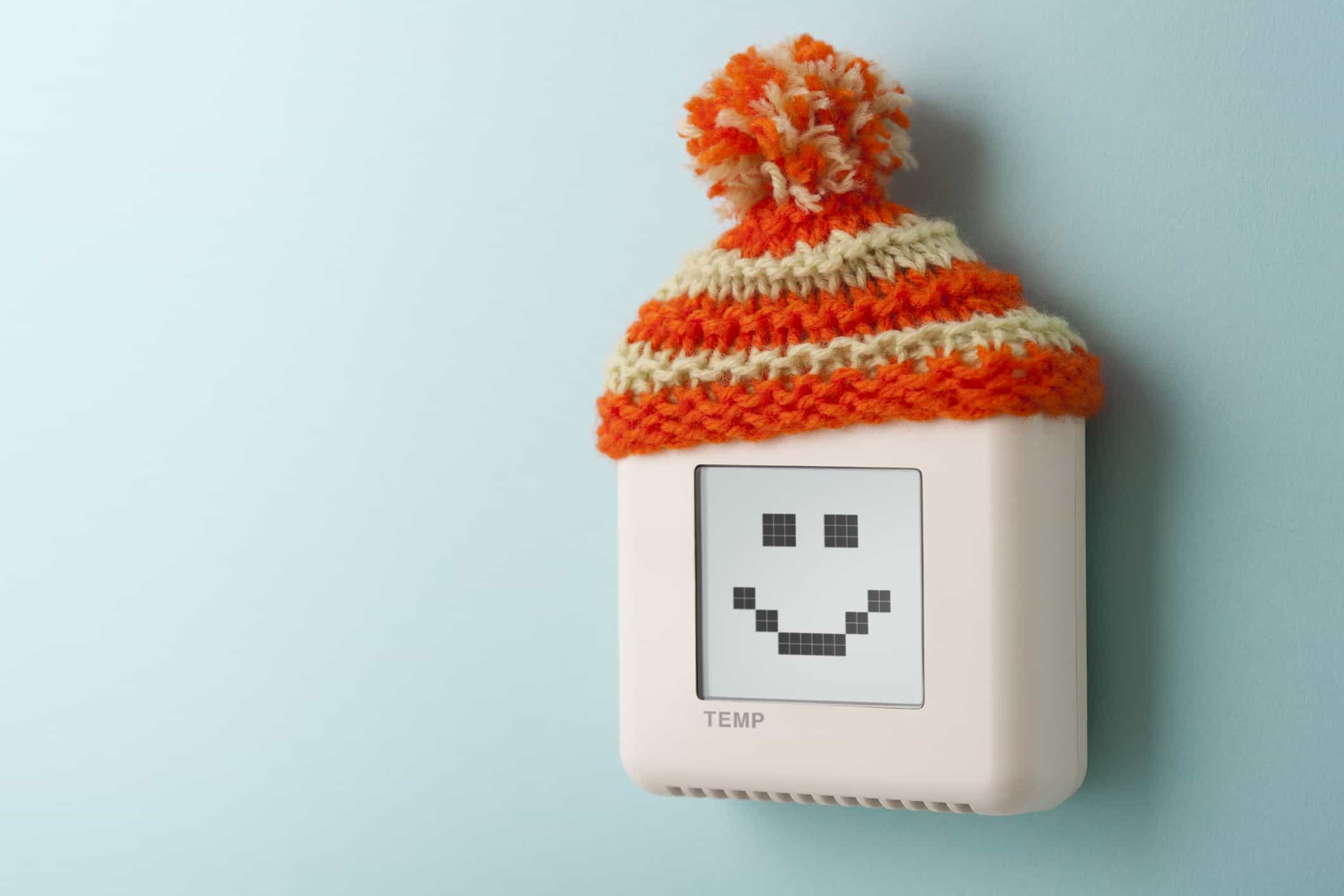 Digital room temperature thermostat with smiley face and wooly hat.