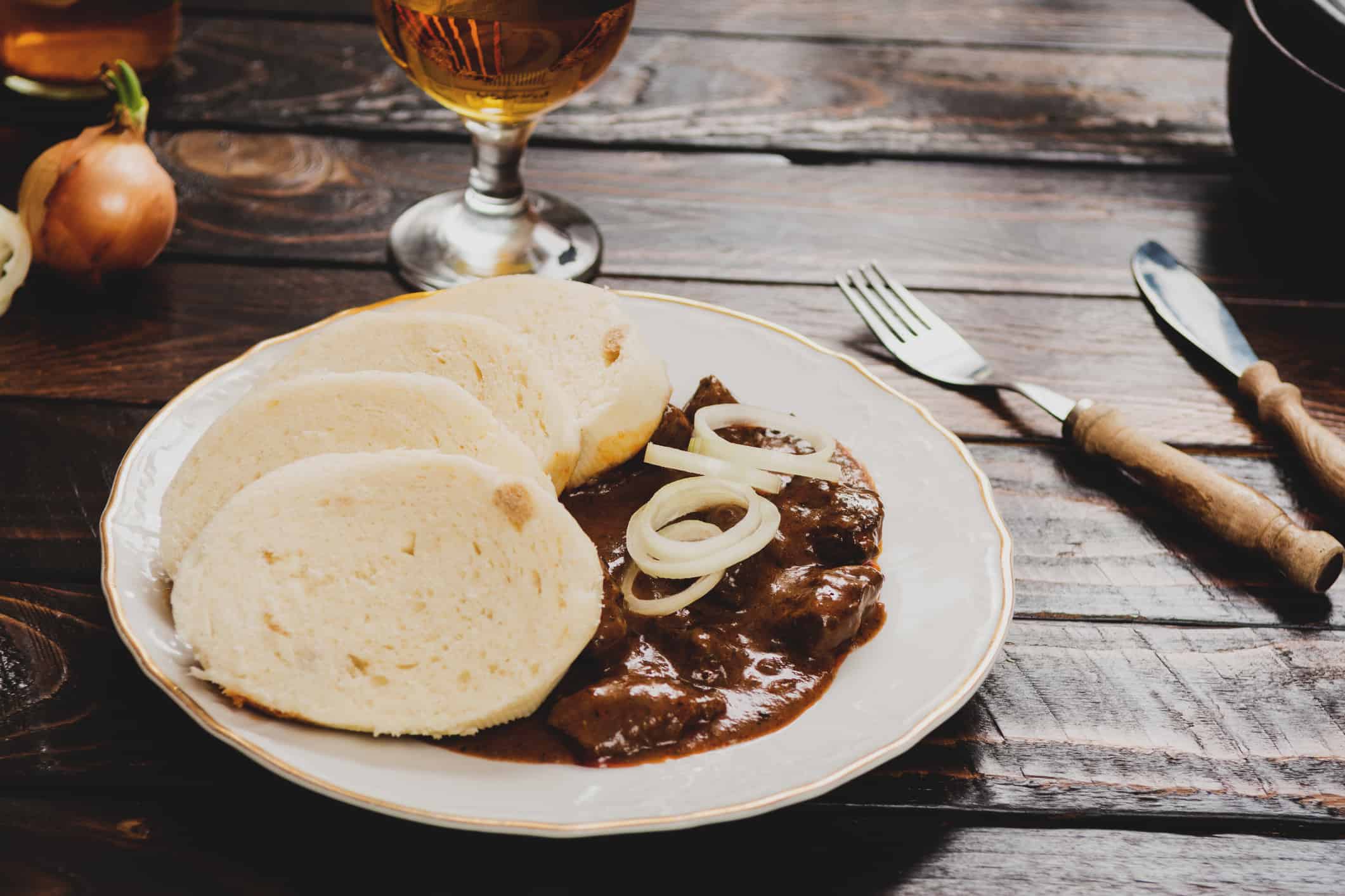 Traditional czech goulash with dumplings and beer on dark table