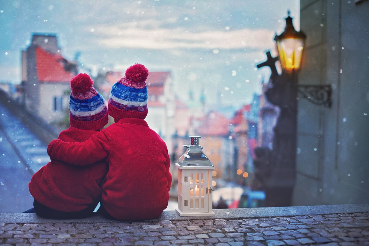 Snow falls in front of two young boys on the streets of Malá Strana.
