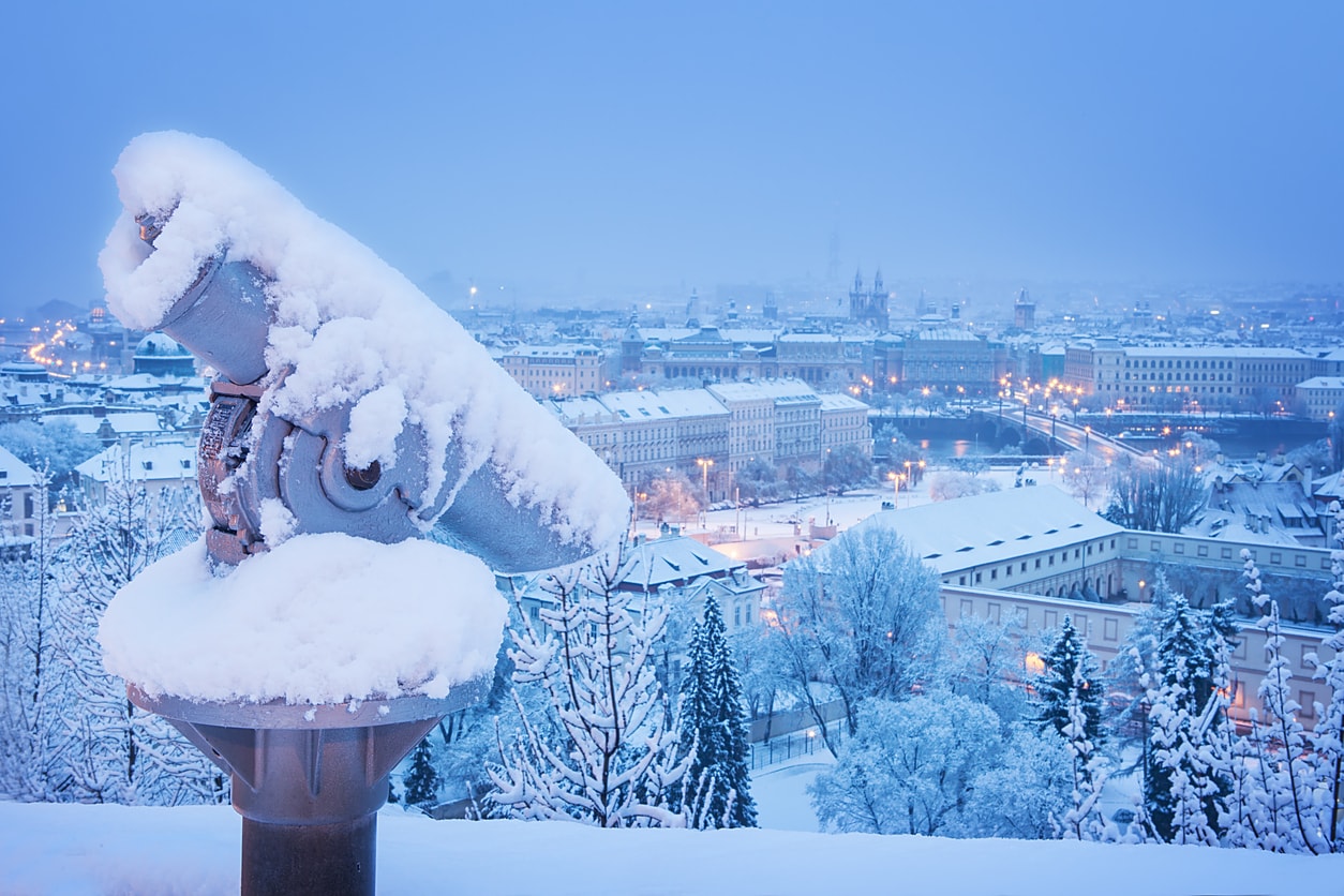 A snow-covered sightseeing Telescope outside Prague Castle overlooking Malá Strana.